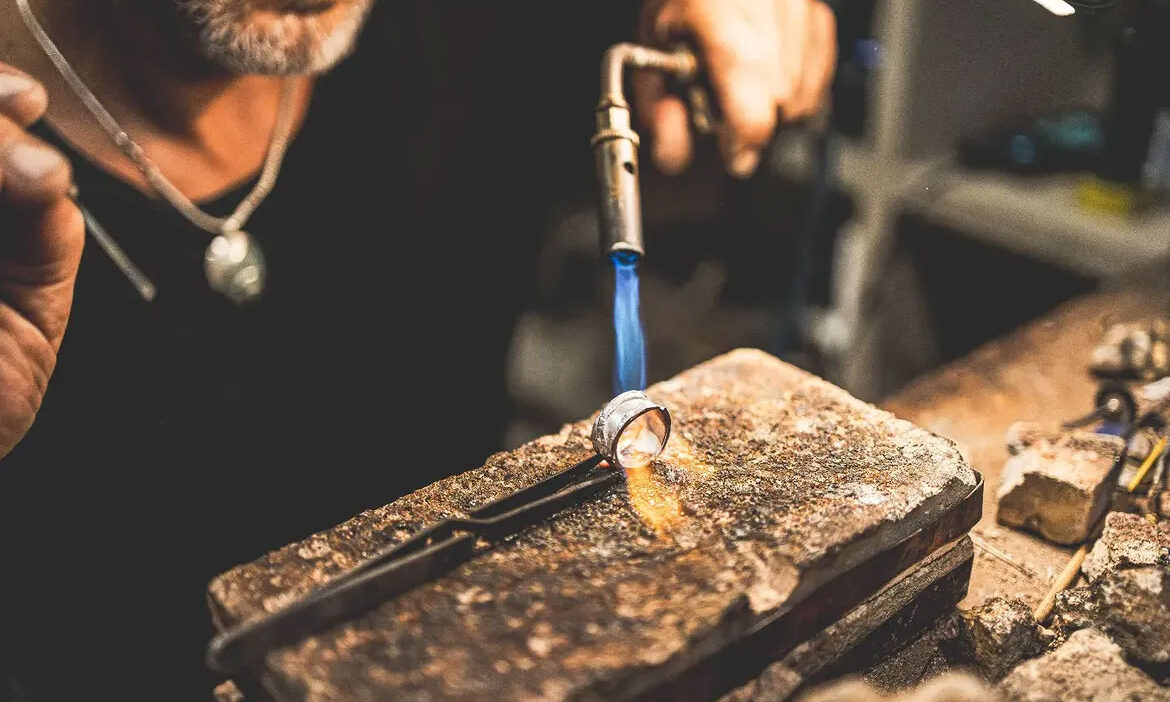 L'orafo che prepara l'argento con la fiamma per creare un gioiello nella bottega Macallè di San Gimignano
