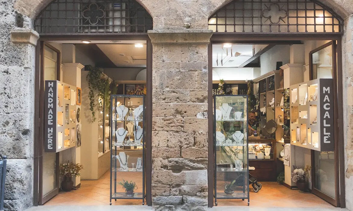 Le due vetrine della bottega Macallè in un palazzo in pietra di San Gimignano, con insegna Handmade Here